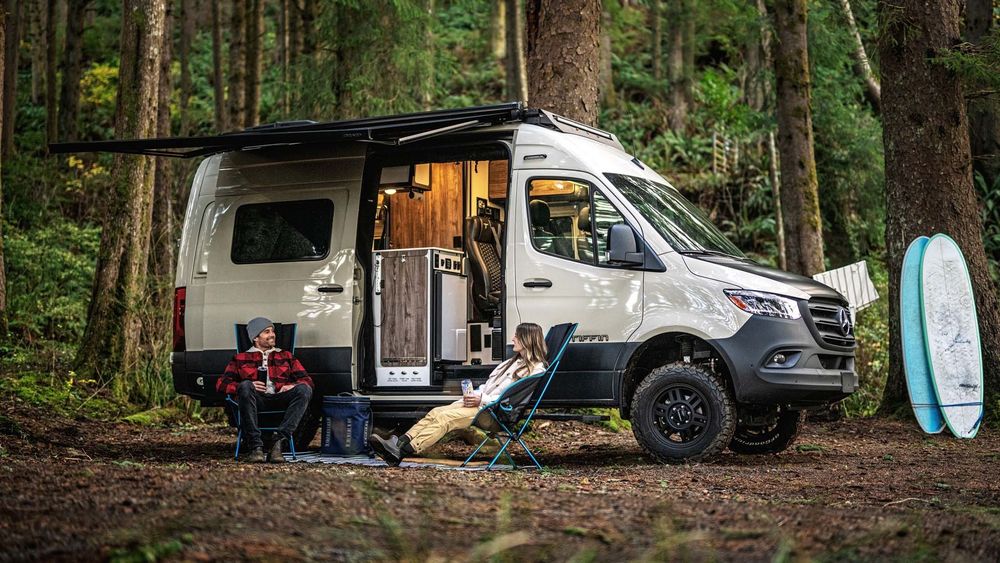 Campervan parked by a lake with a person enjoying the view